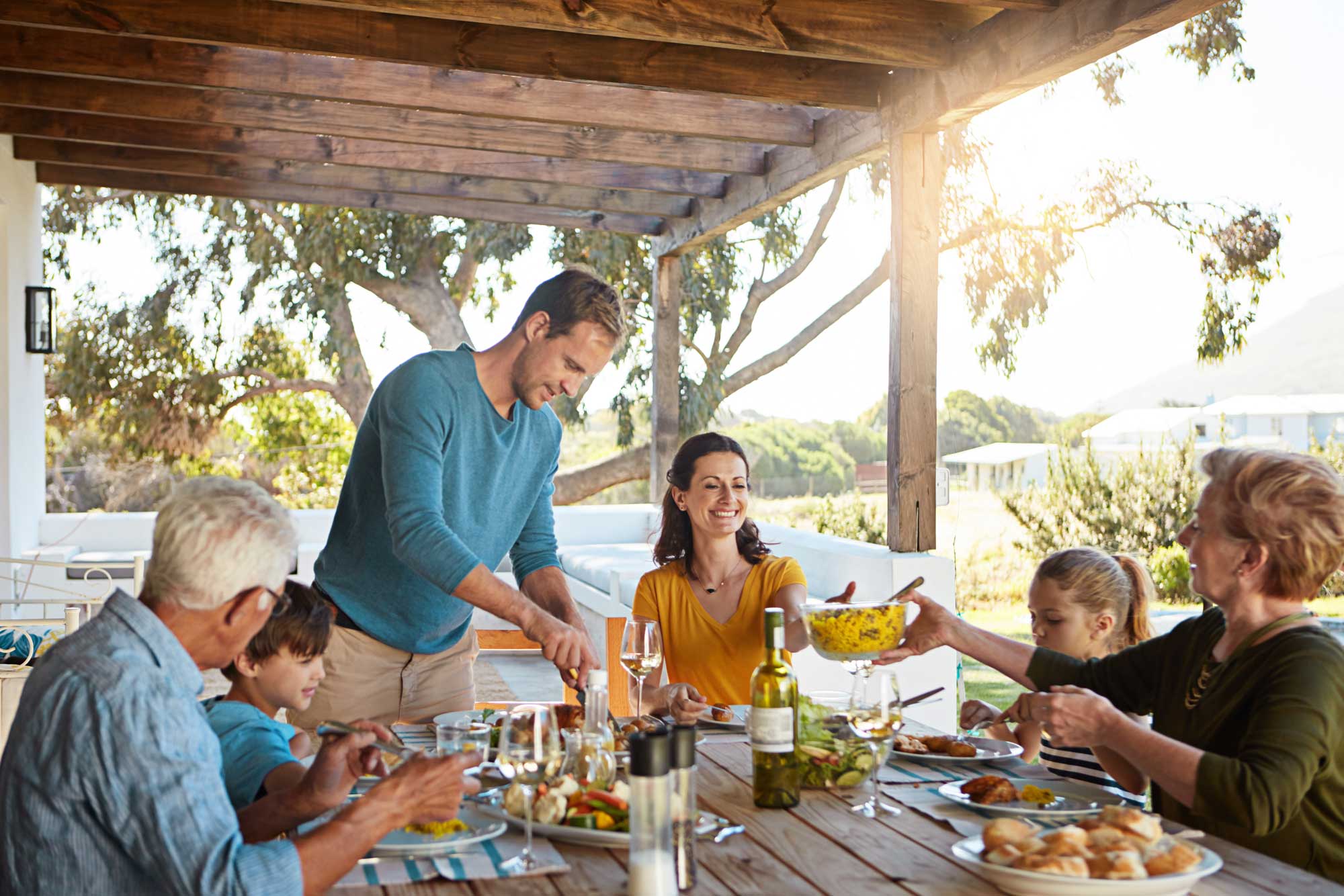 Big family, eating and lunch with food outdoor on patio with conversation, bonding or healthy meal in summer. 